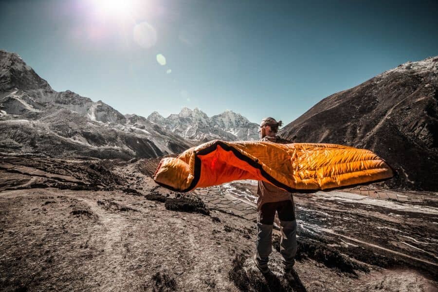 Mann mit Schlafsack mitten in den Bergen