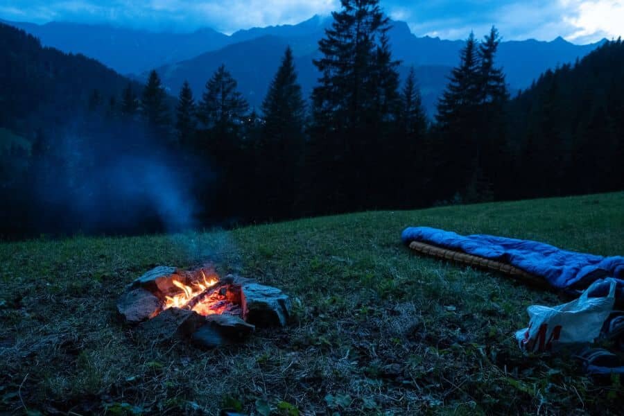 Unter freiem Himmel schlafen mit Lagerfeuer und Blick auf die Berge