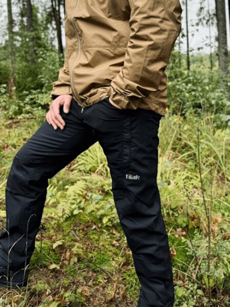 Ein Mann in schwarzen Outdoor-Hosen von Tilak beim Ausflug im Wald. Foto: Rigad
