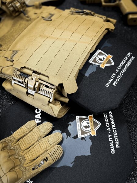 Plattenträger mit eingesetzten ballistischen Platten, Laser-Cut MOLLE und Schnellabziehschnallen; im Vordergrund taktische Handschuhe (PGD).