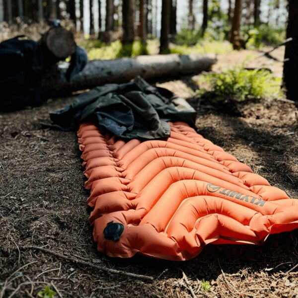 Isolierte aufblasbare Isomatte Static V™ Klymit<sup>&reg;</sup> orange im Wald. Foto: Rigad