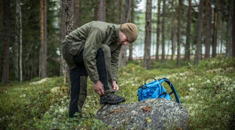Mann in Outdoor-Kleidung im Wald mit Rucksack.