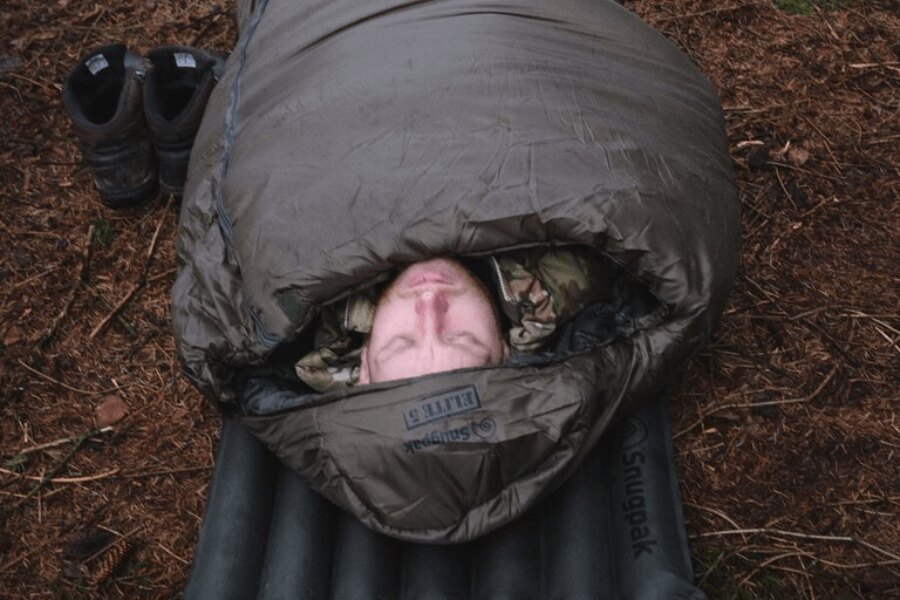 Ein Mann in Tarnkleidung liegt auf einer aufblasbaren Isomatte im Schlafsack Softie<sup>®</sup> Elite 5 Snugpak<sup>®</sup>. Quelle: Rigad, Snugpak