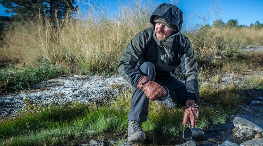 Ein Mann in Handschuhen schöpft Wasser