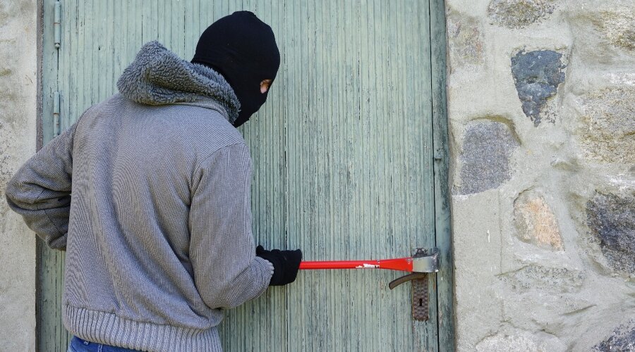 Der Mann dringt mit einem Brecheisen in das Haus ein.