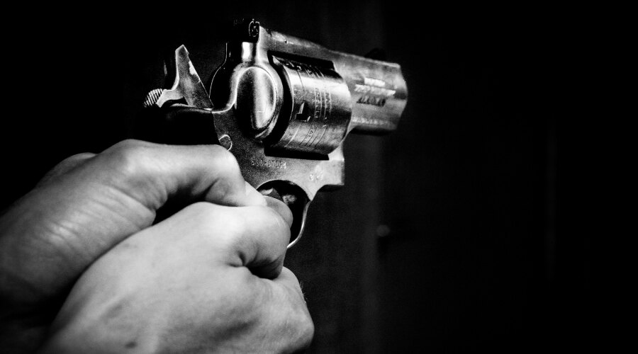 Detail der Hände, die eine Waffe halten