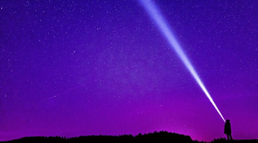 Der Mann leuchtet mit der Taschenlampe in den Himmel.