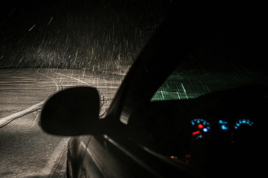 Ein Auto auf der Straße bei Nacht im Schneefall.