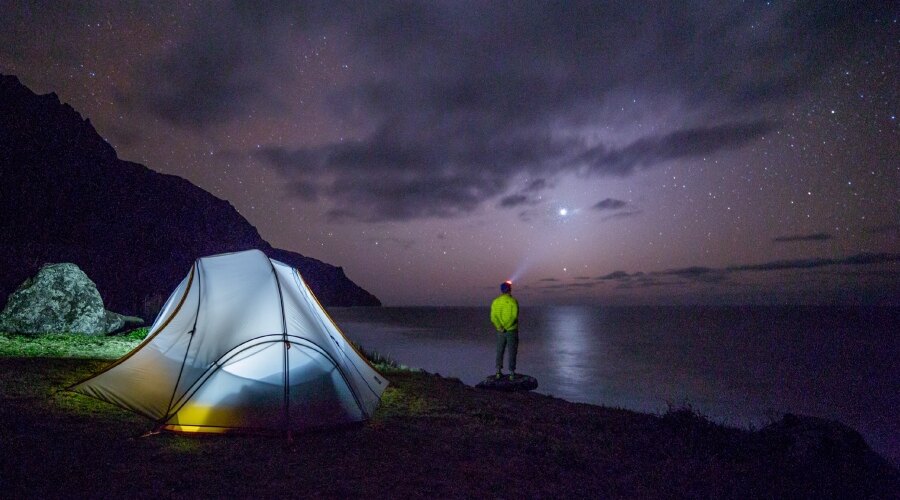 Ein Mann mit einer Stirnlampe schaut in die Ferne auf das Meer.