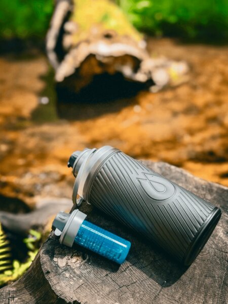 Flux HydraPak Flasche mit Cap-Filter auf einem Baumstumpf in der Natur, ideal für Reisen und Outdoor. Foto: Rigad