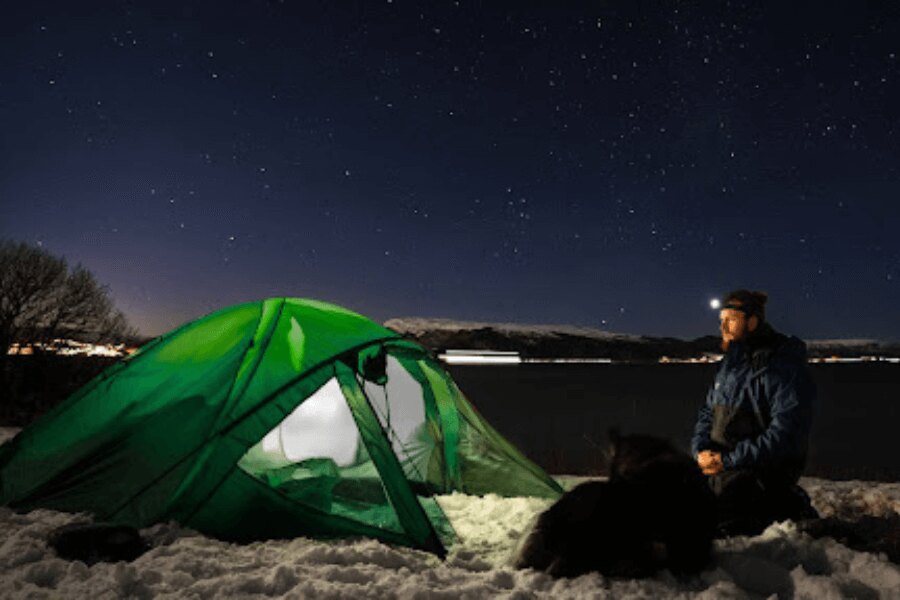 Ein Mann vor dem Zelt, Camping im Schnee.