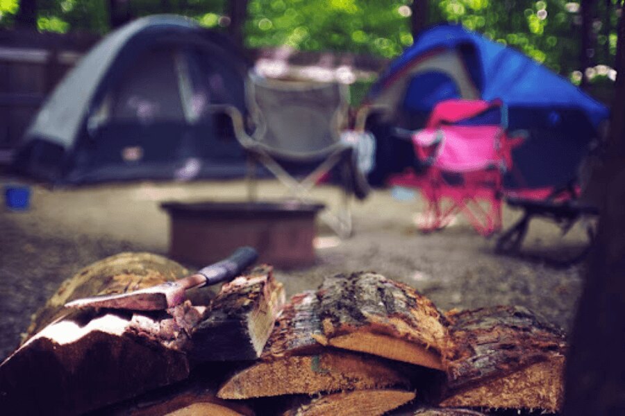 Axt auf Holz am Campingplatz. Quelle: https://www.pexels.com/de-de/foto/holz-landschaft-urlaub-sommer-2662831/