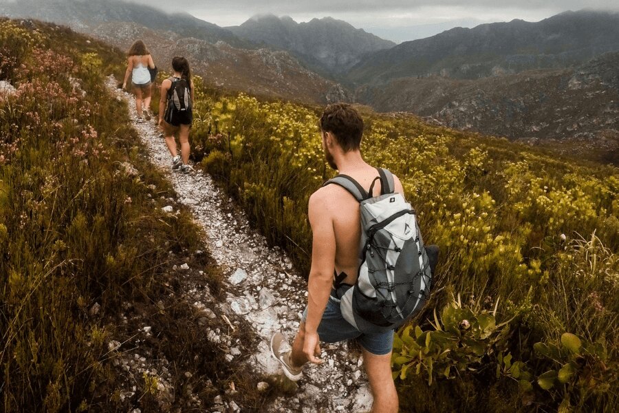 Ein Mann ohne Hemd und zwei Frauen auf einem Bergweg. Quelle: https://www.pexels.com/cs-cz/foto/930685/