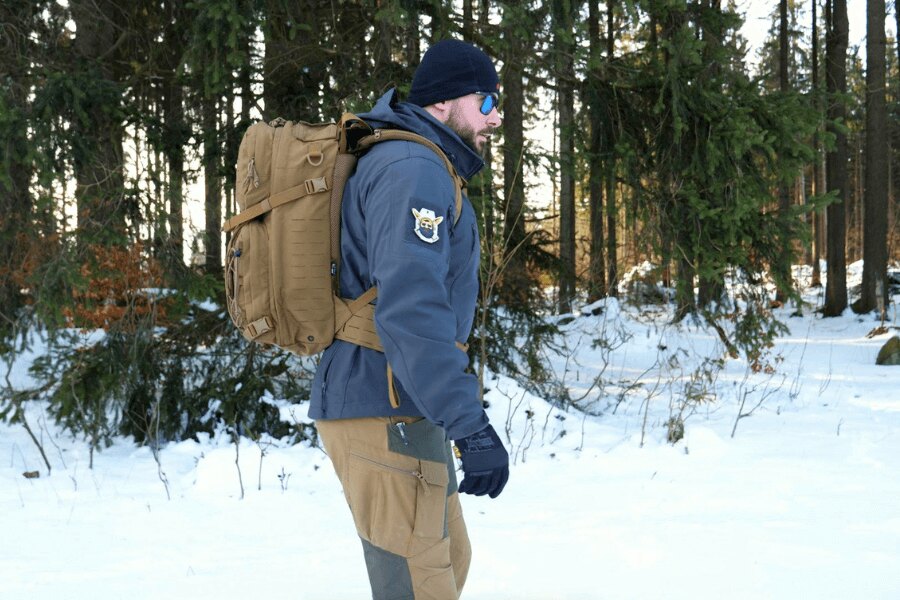 Funktionsjacke und Rucksack im verschneiten Wald. Quelle: Rigad