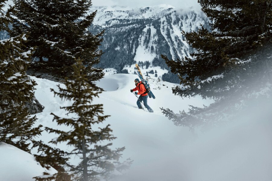 Ein Mann steigt durch die Winterlandschaft mit Skitouren auf dem Rücken.