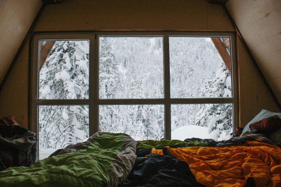 Schlafsäcke am Fenster im Winter in den Bergen in einer Berghütte.