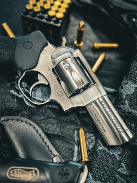 Revolver Ruger GP100 im Kaliber .357 Magnum neben Patronen und Schießholster platziert.