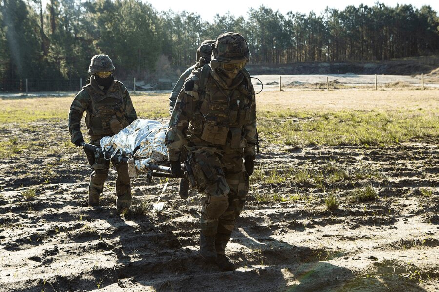 Die Soldaten tragen den Verletzten in einer Trage, abgedeckt mit einer Isotermfolie.
