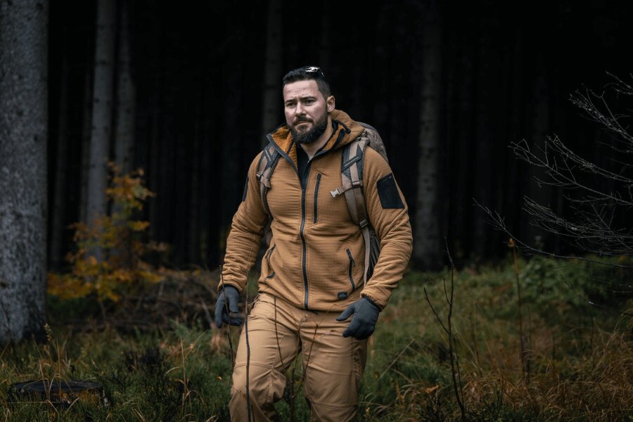 Ein Mann in einem Helikon-Tex Patriot Pro Hoodie beim Marsch durch den Wald – eine Demonstration der leichten und winddichten Stormfleece<sup>®</sup>-Konstruktion. Foto: Rigad