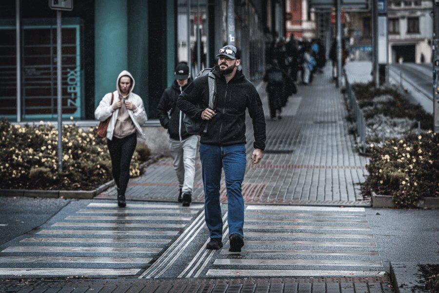 Mann in einem schwarzen Helikon-Tex Patriot Pro Hoodie beim Stadtspaziergang – technischer Hoodie im zivilen Stil für den täglichen Gebrauch. Foto: Rigad