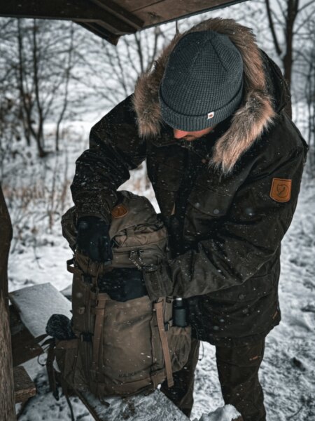 Robuster Expeditionsrucksack Fjällräven Kajka im Schnee liegend, bereit für eine mehrtägige Wintertour. Foto: Rigad