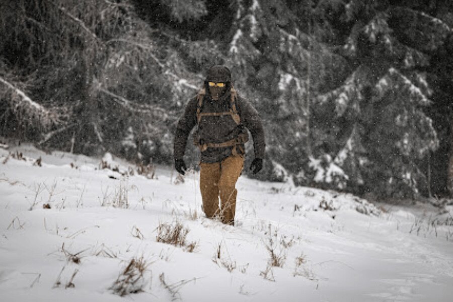 Ein Bergwanderer, der durch tiefen Schnee bei eingeschränkter Sicht während einer Winterwanderung geht. Foto: Rigad