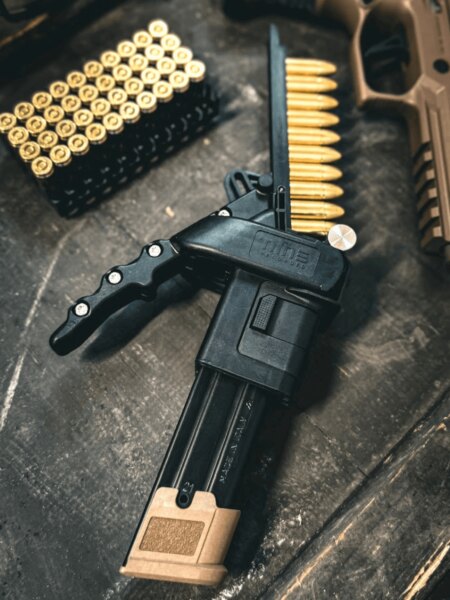 Magazinlader Nine Reloaded neben 9-mm-Luger-Munition und Pistole.