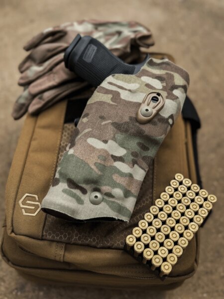 Munition Kaliber 9 mm Luger neben einer Pistole in einem Tarnholster auf der Schießausrüstung.
