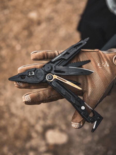 Leatherman MUT Multitool geöffnet auf einer Hand in einem taktischen Handschuh.