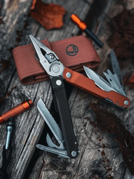 Leatherman Rebar Multifunktionswerkzeug mit ausgeklappten Zangen und ausgefahrenen Werkzeugen auf einer Holzoberfläche.