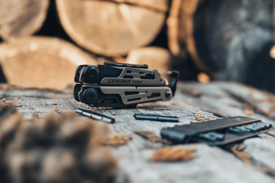 Leatherman Signal auf einem Holztisch mit Bits und Zubehör in einer Outdoor-Umgebung.