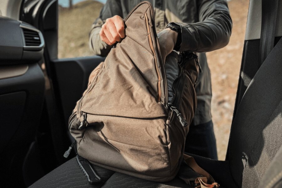 Der Benutzer öffnet den auf dem Autositz liegenden Vertx Gamut-Rucksack.