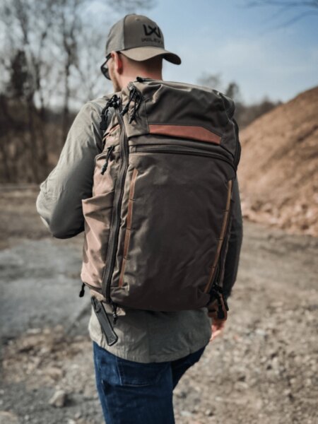 Ein Mann mit einem Vertx Gamut -Rucksack auf dem Rücken während der Bewegung im Gelände.