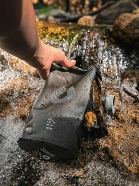 Füllen des weichen HydraPak-Hydratationsbeutels mit Wasser aus einem Gebirgsbach.