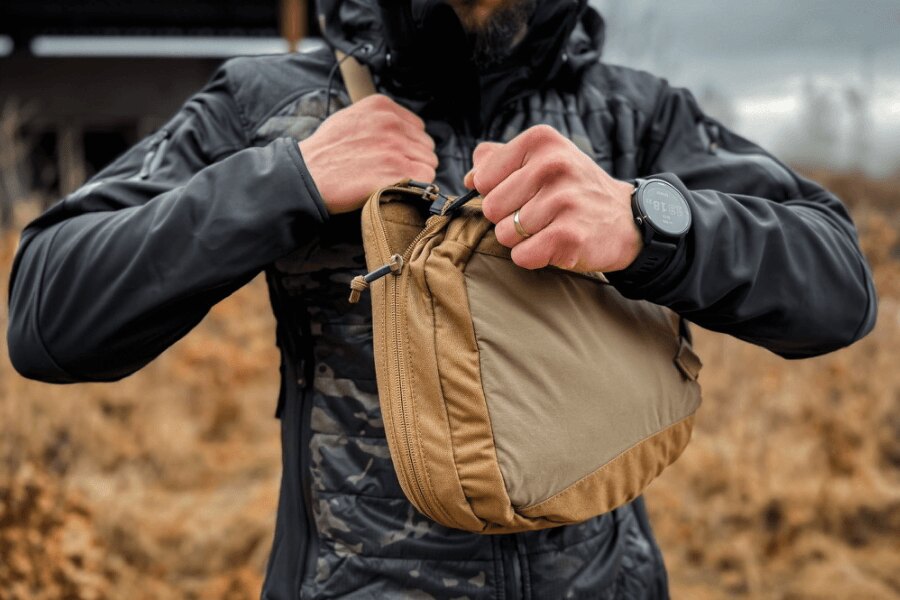 Öffnen der Haupttasche des Sling Bags mit einem einzigen Zug am Reißverschluss vor dem Ziehen der Pistole.
