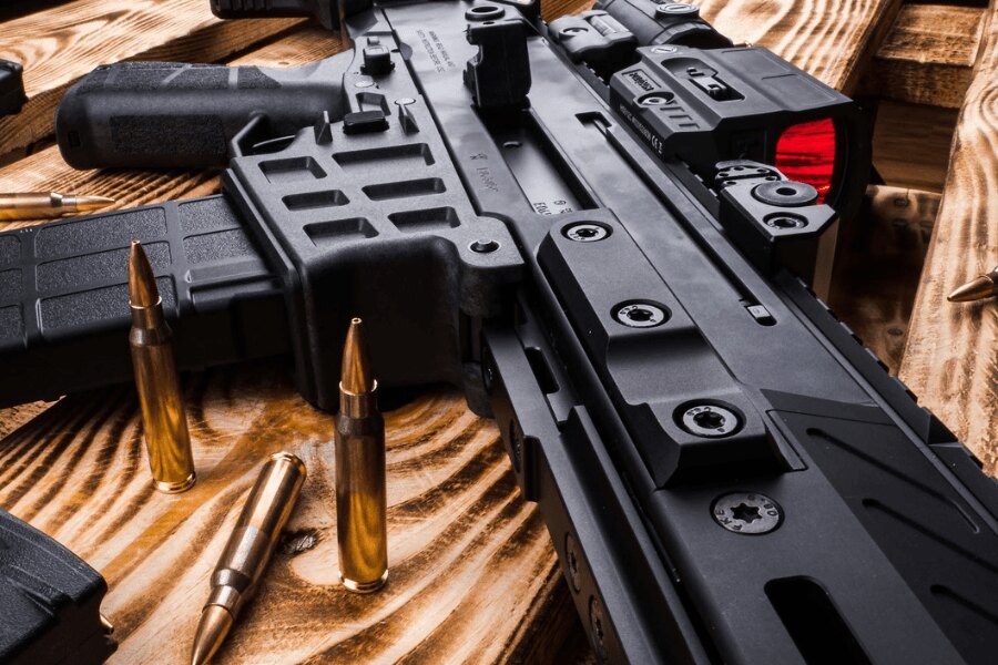 Detail des Selbstladegewehrs CZ BREN 2 mit einem Rotpunktvisier auf einem Holztisch.