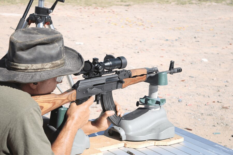 Ein Schütze zielt mit einem rumänischen Gewehr der Reihe WASR, ausgestattet mit Zielfernrohr und Mündungsbremse, auf einem Außenschießstand.