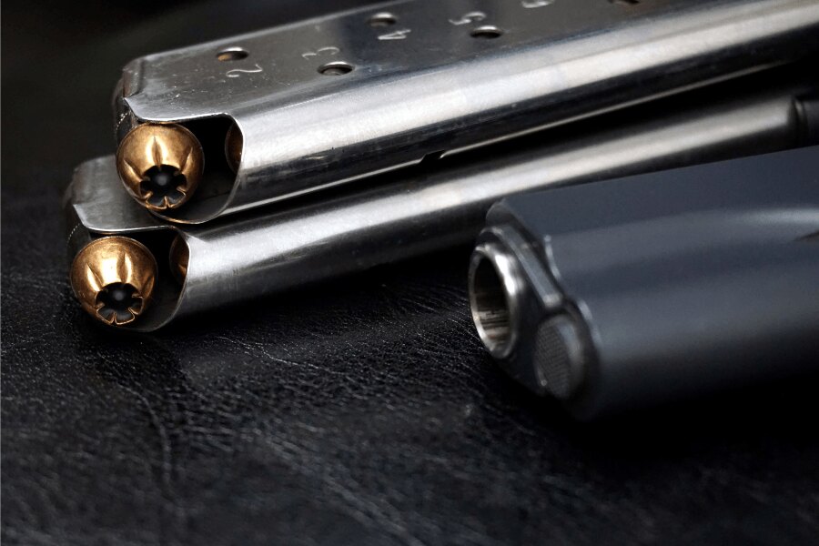 Detail der Magazine der Pistole M1911 mit .45 ACP Patronen und einem Teil der Pistole im Hintergrund.