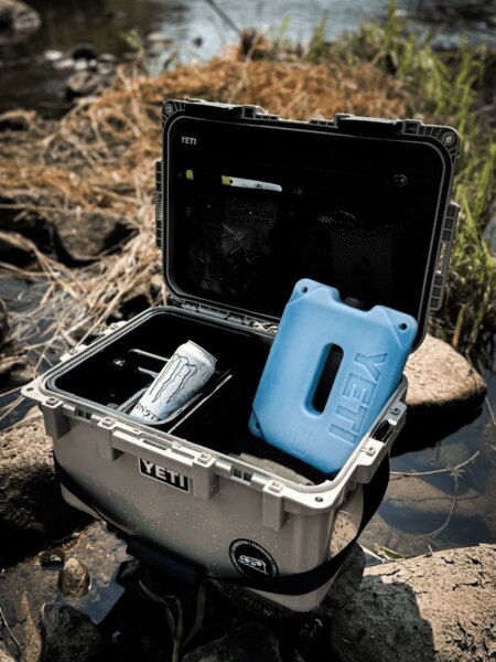 Offener Transportkoffer YETI LoadOut GoBox mit Kühlakkueinsatz und Getränk.