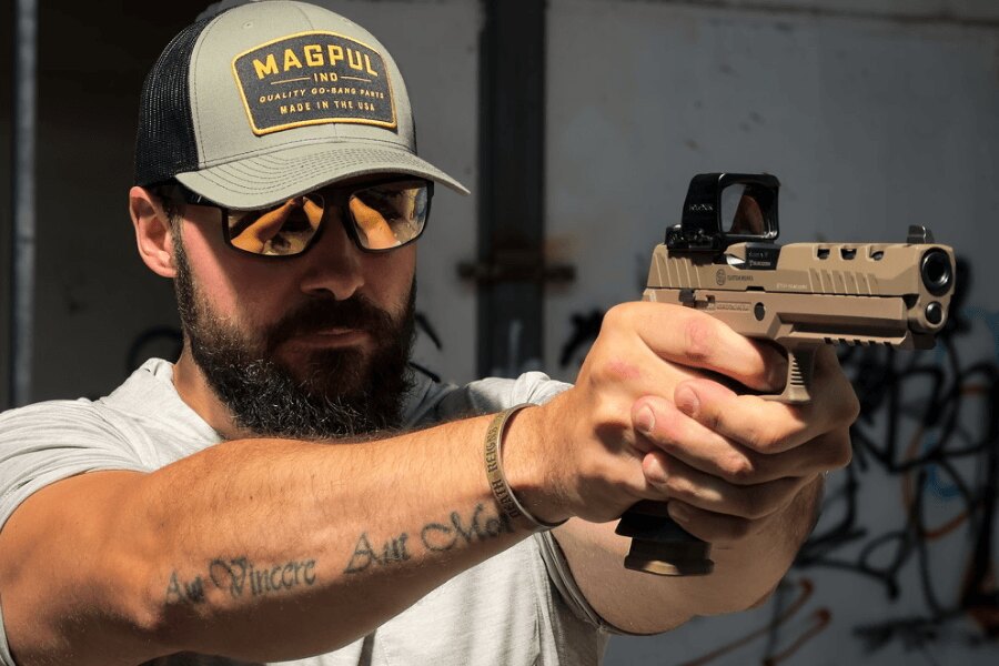 Der Schütze mit Schutzbrille zielt mit einer SIG Sauer P320 DH3 Pistole mit einem Holosun-Visier.