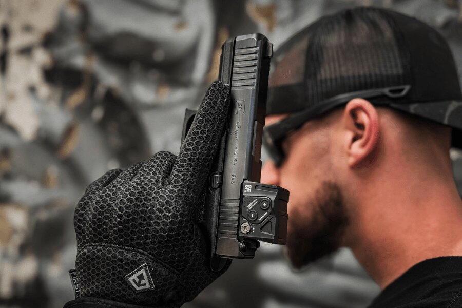 Detail der Glock 45 Pistole mit einem Kollimator, gehalten in einem Handschuh.