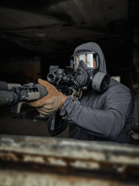 Der Schütze in einer Vollgesichtsmaske AVEC mit Filter beim Zielen mit einem Gewehr.