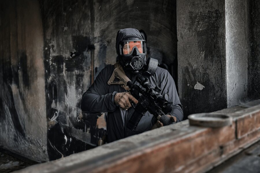 Ein Benutzer in einer Vollgesichtsmaske AVEC mit Filter und Gewehr in einem Industrieobjekt.
