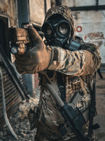 Schütze in einer Vollgesichtsmaske mit Filter beim Zielen mit einer Pistole.